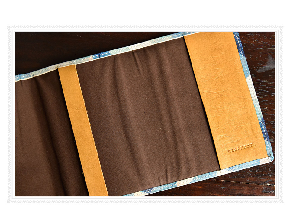 ブックカバーの内側、ブラウンの綿生地と、右側の革の下部に入ったHIRAMEKI.のブランドロゴの刻印イメージ